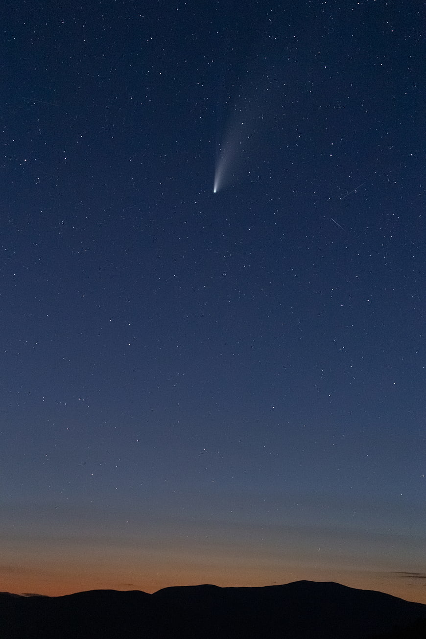 Comet in Starry Night Sky Over Mountain Silhouette