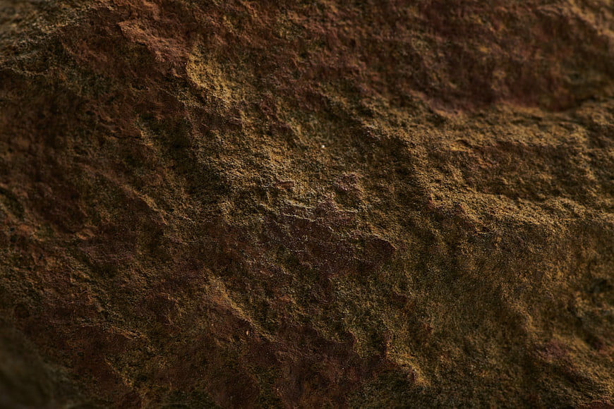 Close-up texture of rough brown and green rock surface