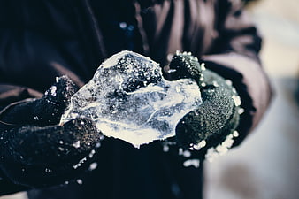 Gloved Hands Holding Chunk of Clear Ice in Winter