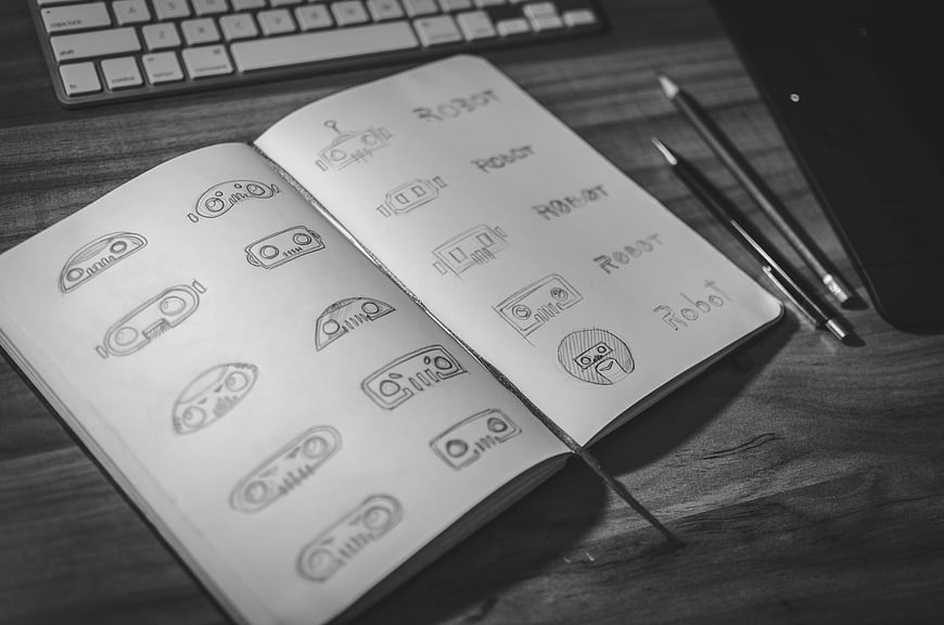 Hand-drawn robot logo sketches in notebook on desk