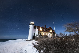Illuminated Lighthouse And House Under Starry Winter Night Sky