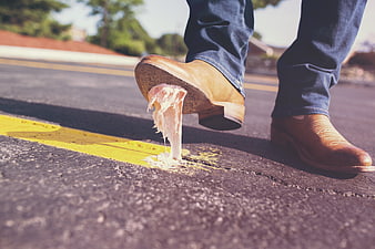 Man's shoe stuck to bubble gum on asphalt road