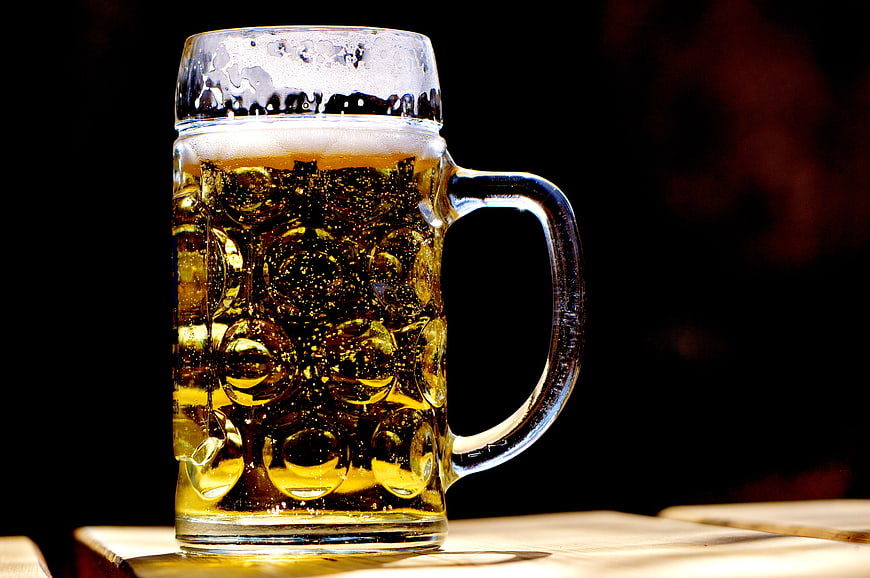 Chilled Beer Mug With Foam On Wooden Table Against Black Background