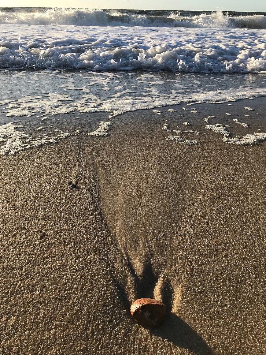 Rusty Object on Wet Sand with Ocean Waves