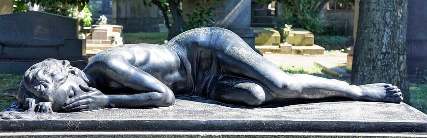 Bronze statue of reclining grieving woman in cemetery
