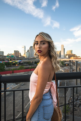 Stylish Blonde Woman in Pink Top on Urban Rooftop