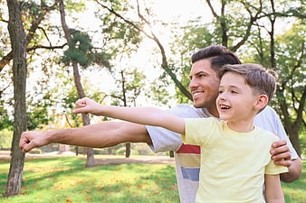 Happy Father and Son Pointing Together in Park