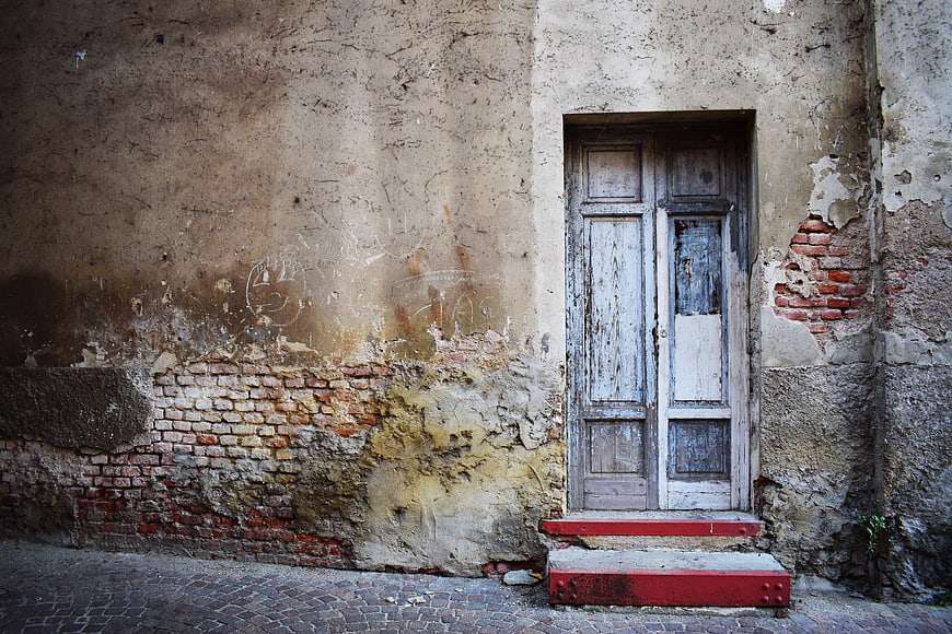 Old weathered wooden door in crumbling brick wall