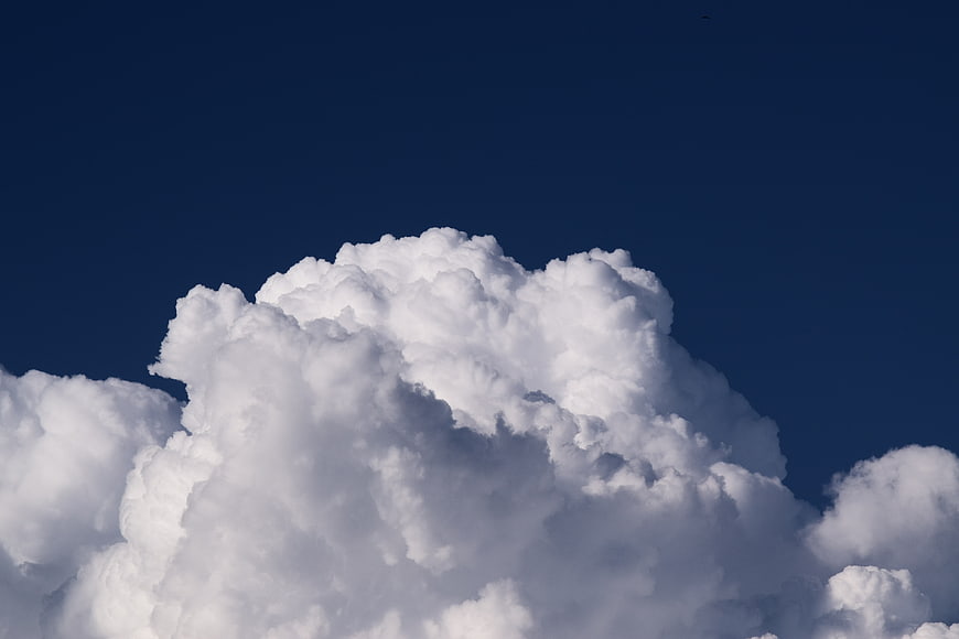 Dramatic white cumulus clouds against deep blue sky