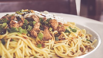 Close-up of Asian noodle dish with chicken, scallions, and egg