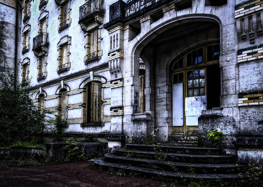 Abandoned Hotel Facade With Overgrown Steps And Weathered Architecture