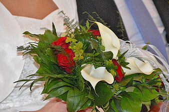 Bride holding red rose and white calla lily bouquet