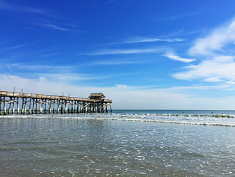Long wooden pier extending into ocean on sunny day