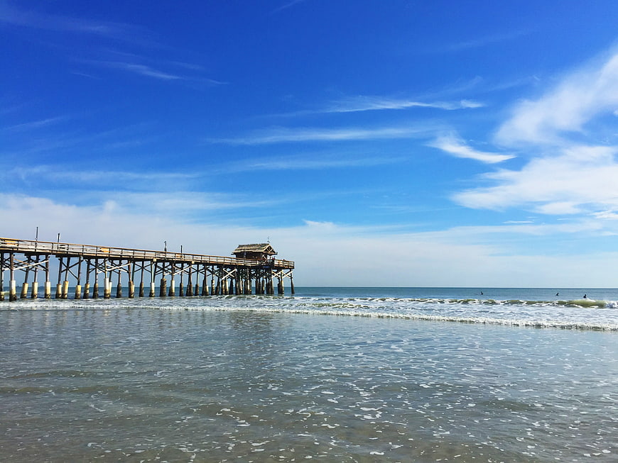 Long wooden pier extending into ocean on sunny day