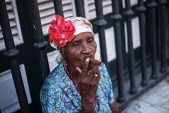 Senior Cuban woman smoking cigar with red flower headscarf