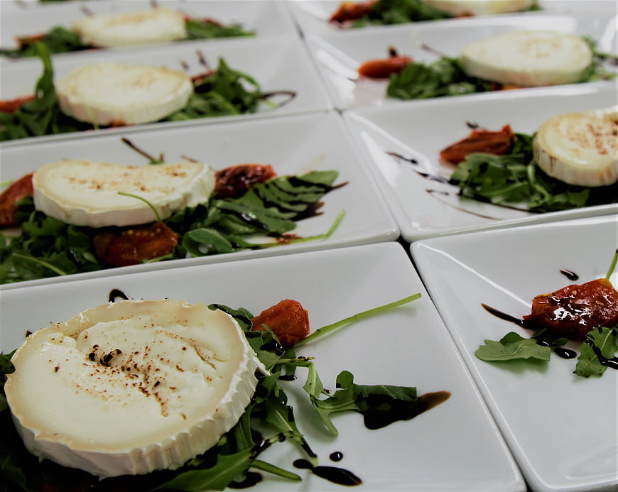 Plates of Baked Brie with Arugula and Sun-Dried Tomatoes