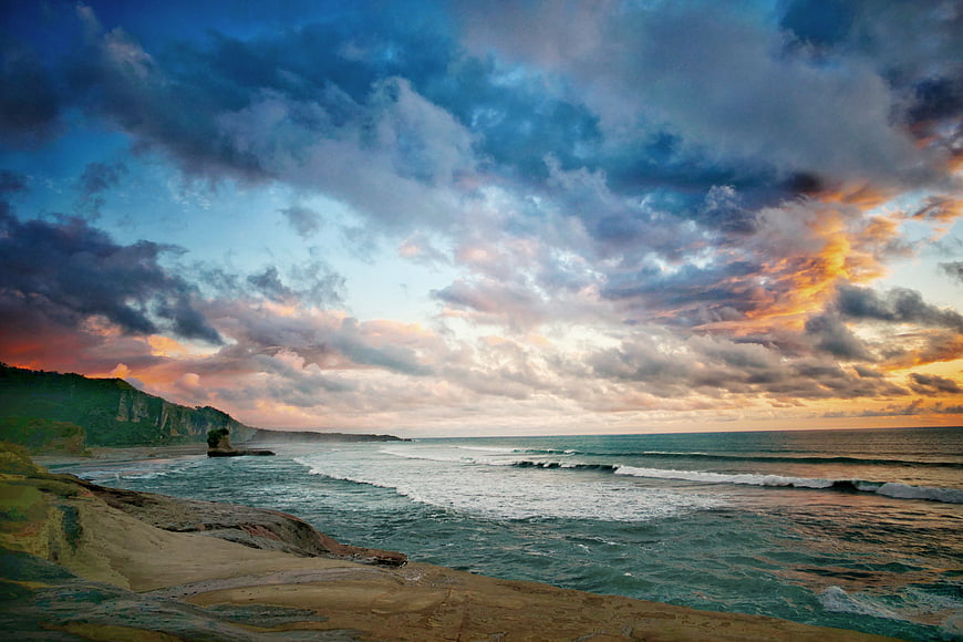 Dramatic Coastal Sunset with Rocky Cliffs and Ocean Waves