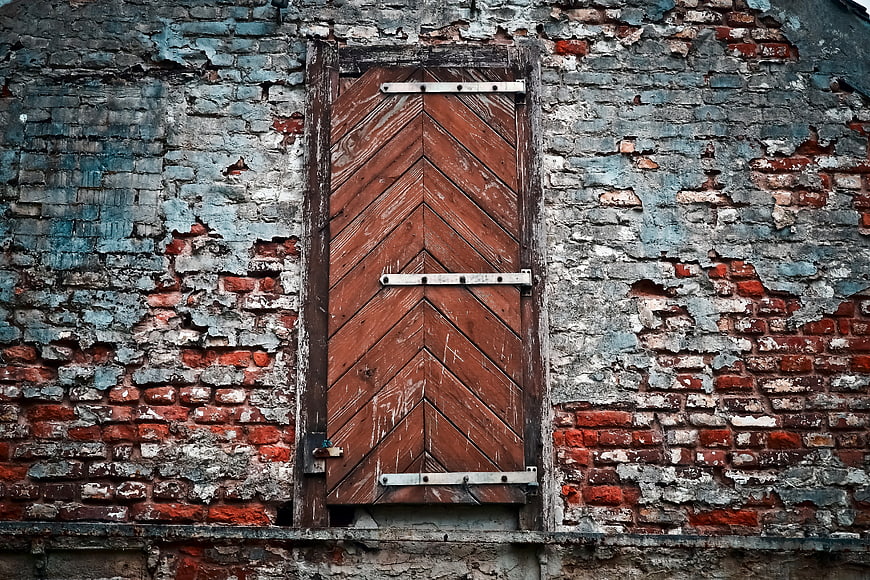 Weathered Wooden Door on Dilapidated Brick Wall