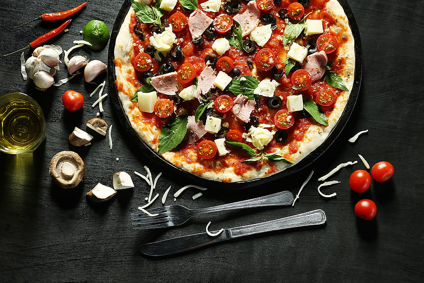 Uncooked Pizza with Fresh Ingredients on Dark Table