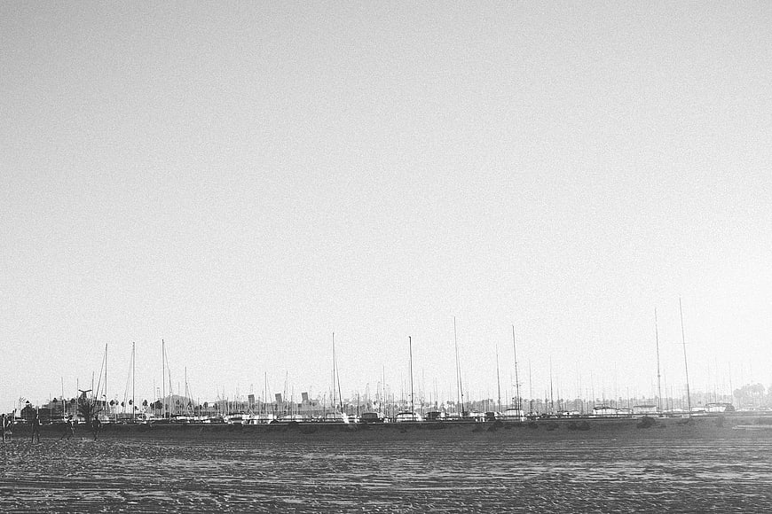 Black and white sailboats in harbor on beach