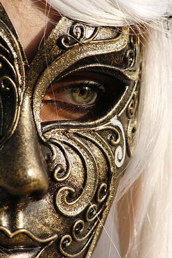 Close-up of eye through ornate gold Venetian carnival mask