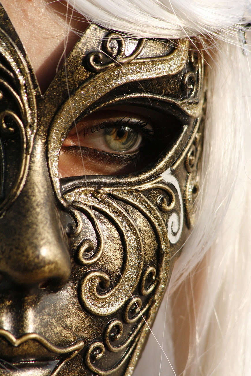 Close-up of eye through ornate gold Venetian carnival mask