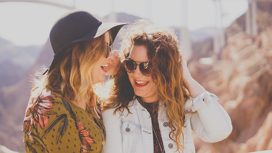 Two Happy Women Laughing Together Outdoors in Sunlight