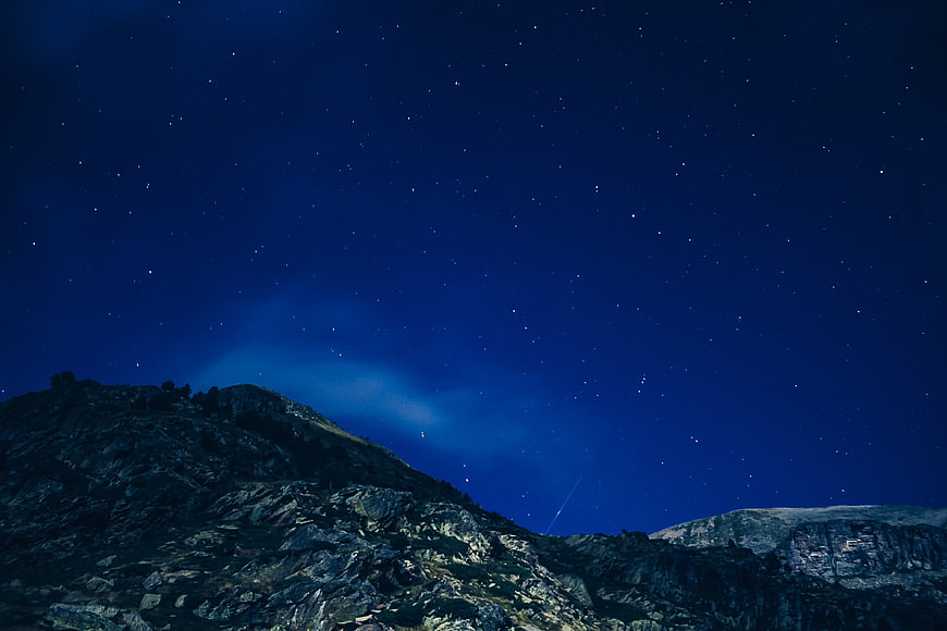 Starry Night Sky Over Rocky Mountain Landscape