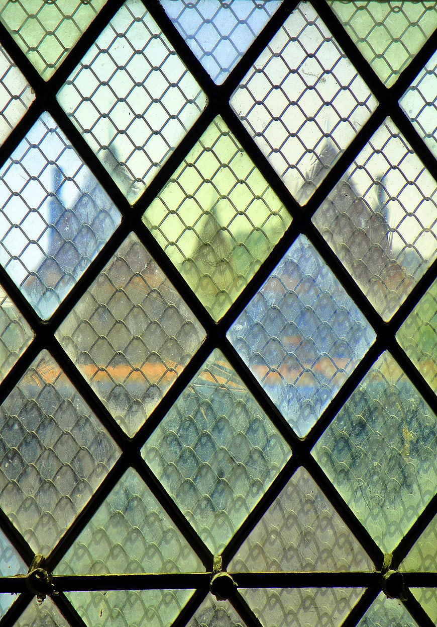 Close-up of diamond-paned stained glass window with green and blue hues