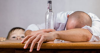 Drunk father passed out at table with child watching