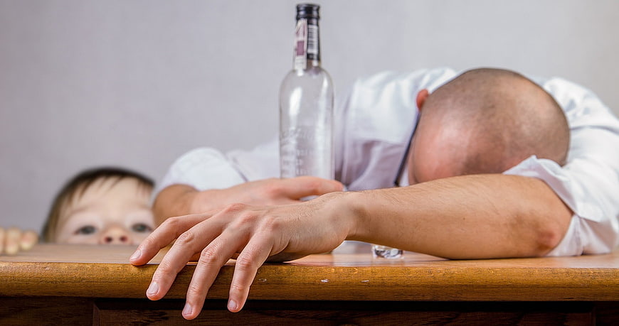 Drunk father passed out at table with child watching