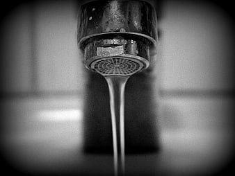 Black and white close-up of a rusted metal faucet with a water stream