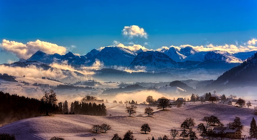 Snowy Alpine Valley with Morning Mist and Mountains