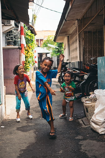 Three happy children playing in a narrow street