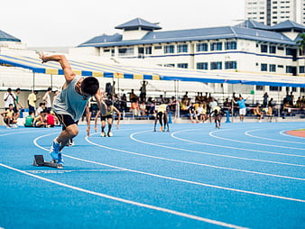 Male Sprinter Launching from Starting Blocks on Blue Track
