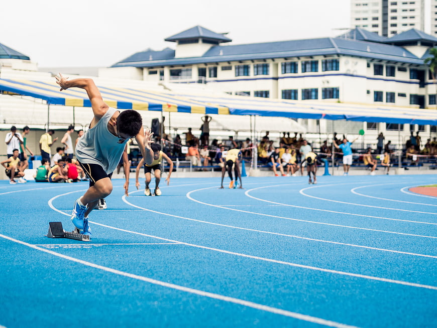 Male Sprinter Launching from Starting Blocks on Blue Track