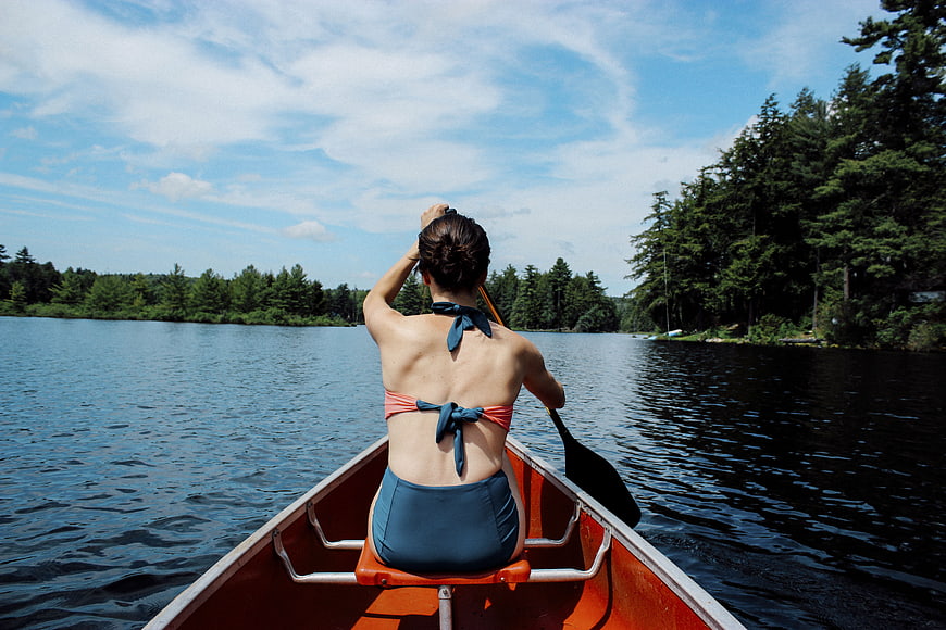 Woman in Vintage Bikini Rowing Canoe on Lake