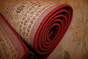 Close-up of rolled vintage Persian rug with red border
