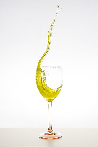 Green liquid splash in wine glass on white background