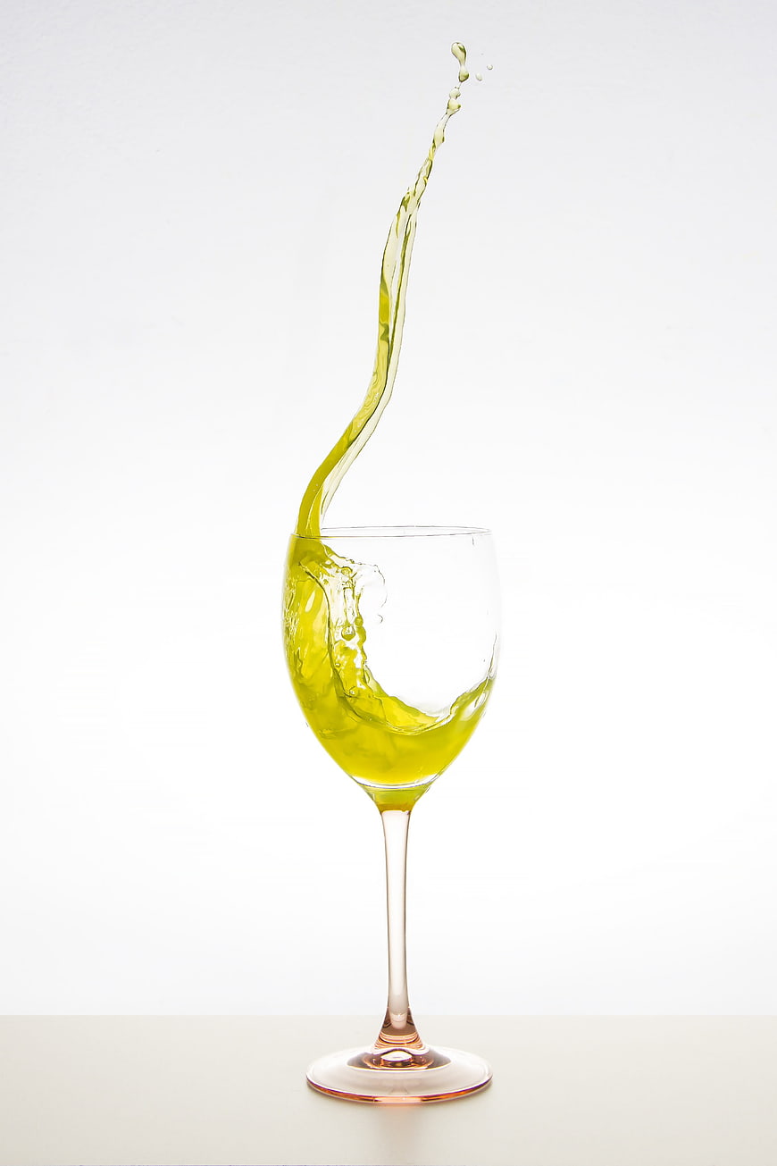 Green liquid splash in wine glass on white background