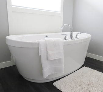 Modern white freestanding bathtub with chrome faucet and towel
