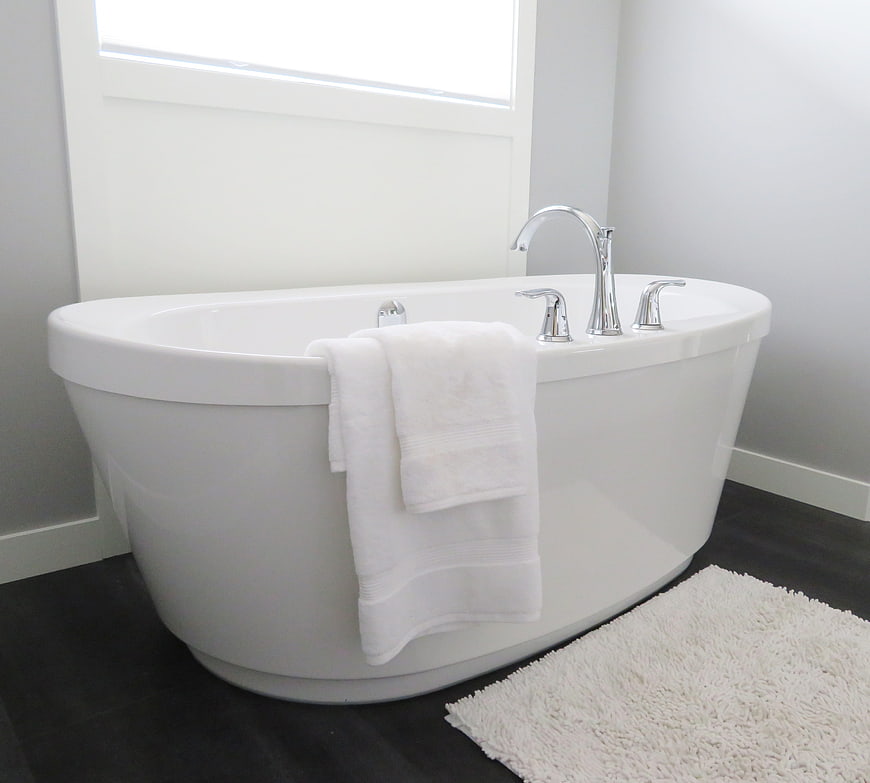 Modern white freestanding bathtub with chrome faucet and towel