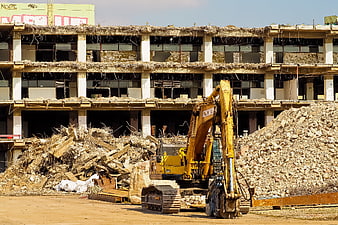 Yellow Excavator Demolishing Building Amidst Rubble Pile