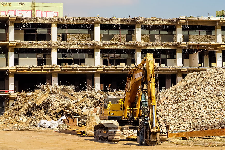 Yellow Excavator Demolishing Building Amidst Rubble Pile