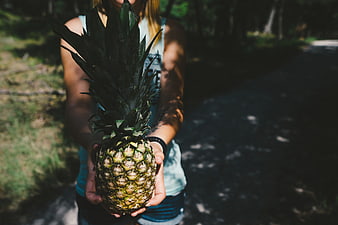 Woman holding pineapple in forest path
