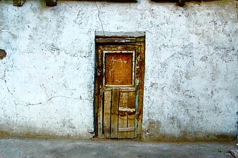 Old weathered wooden door in cracked white wall