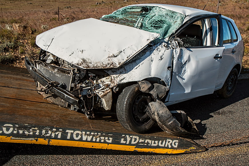 Wrecked white car on tow truck ramp