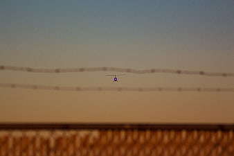 Helicopter flying at sunset behind power lines