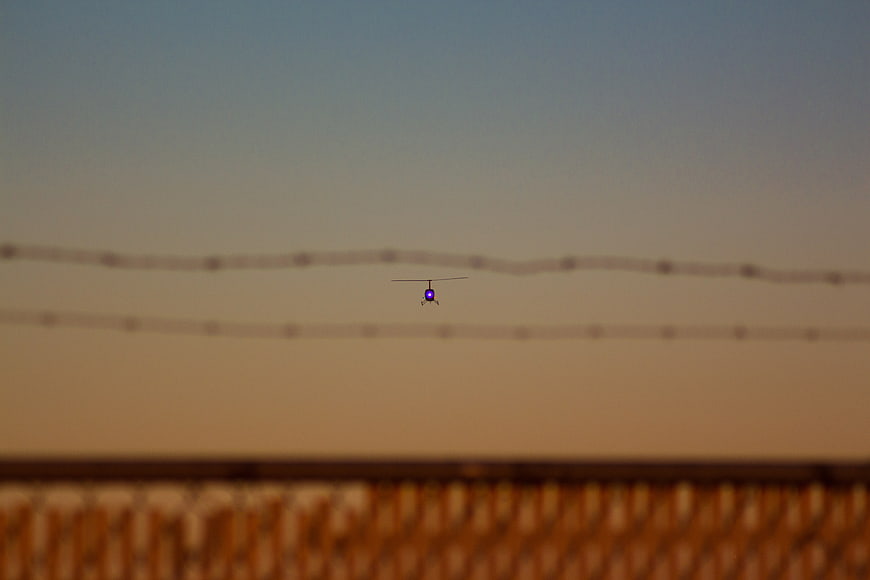 Helicopter flying at sunset behind power lines