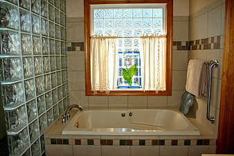 Spacious bathroom with glass block wall and stained glass window